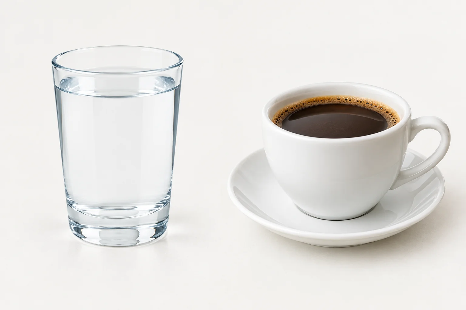 Um copo com água ao lado de uma xícara com café.