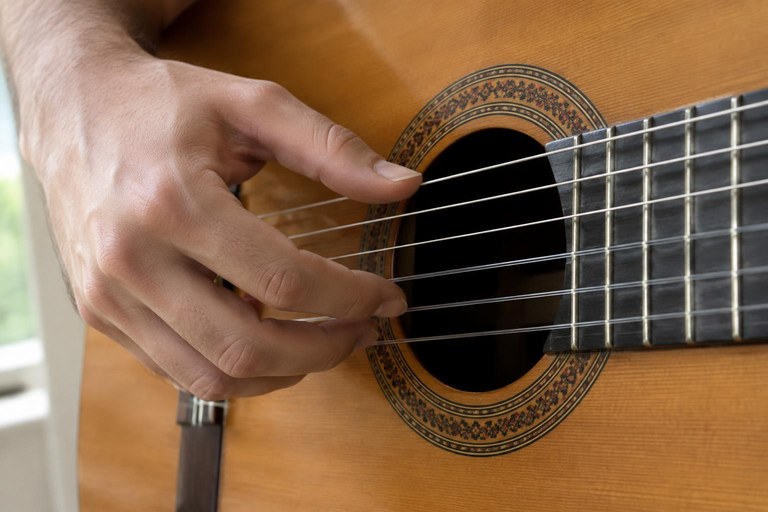 Mão direita sobre a boca do violão com o polegar na corda grave e os dedos indicador, médio e anular encostados nas cordas três, dois e um