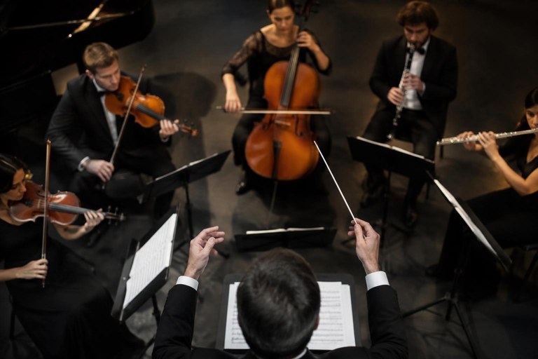 Maestro coordenando músicos de instrumentos diferentes, representando a orquestração de agentes especializados