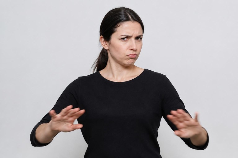 A signer shaking their head with pressed lips while tossing both hands palm down for a negative