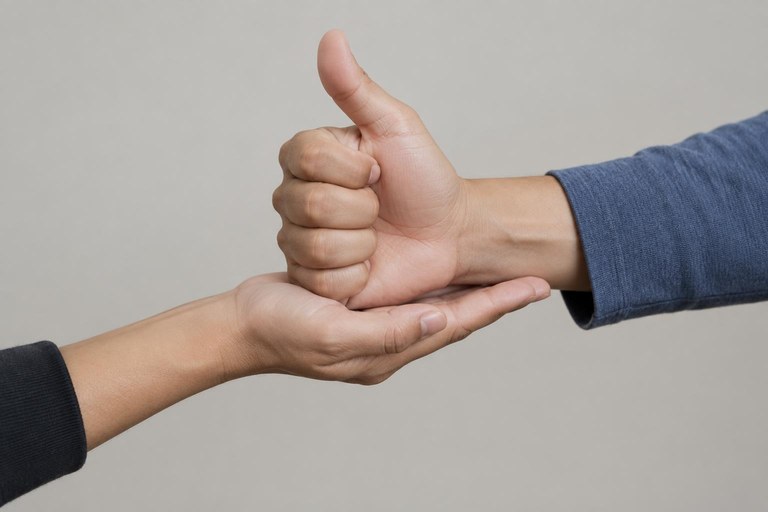 Hands demonstrating the directional HELP sign moving outward