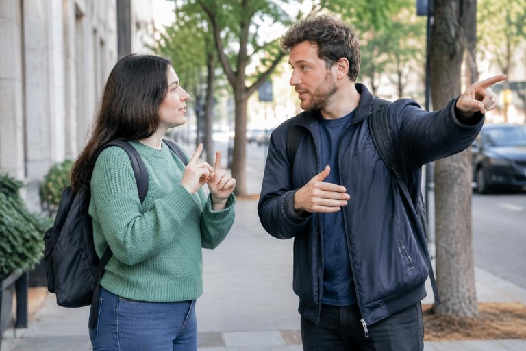 One person giving directions in sign language to another on a sidewalk